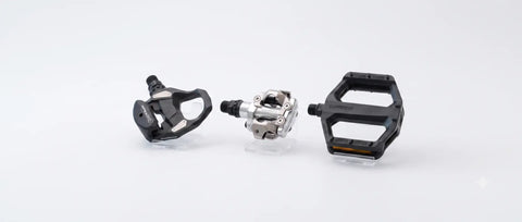 Tre Shimano-sykkelpedaler, med sort og sølv metallisk finish og tydelige design for ulike kjørestiler.